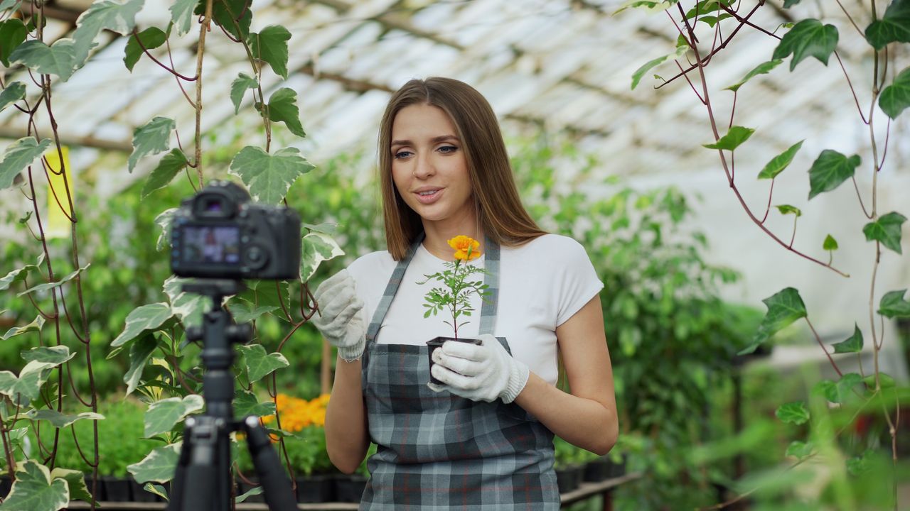 services-03 Young gardener filming a plant care tutorial in a bright greenhouse setting.