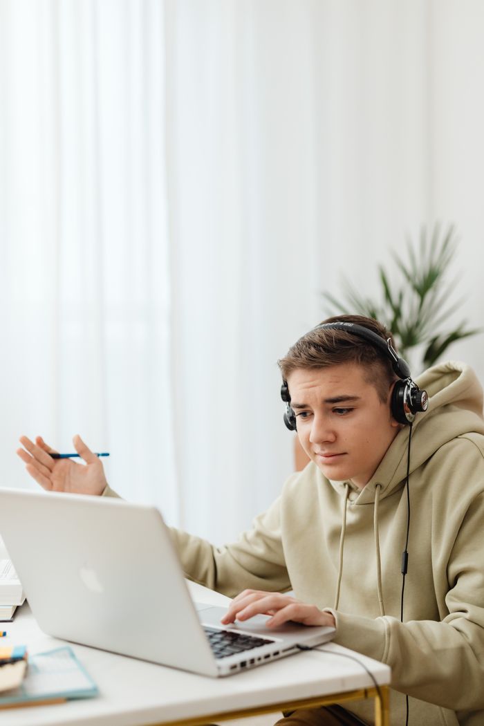services-02 Teenager in hoodie using laptop for online learning at home.